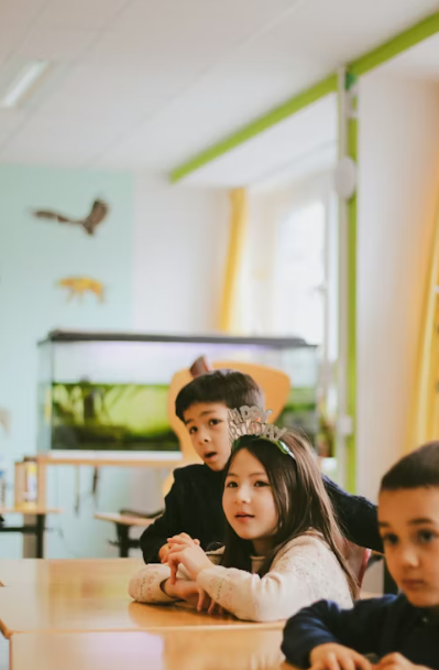 An elementary classroom with a teacher and students engaged with a projected lesson